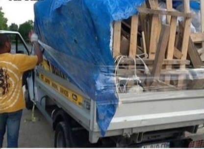 Camionnette chargée de bois et de gravats, bâchée avant le départ
